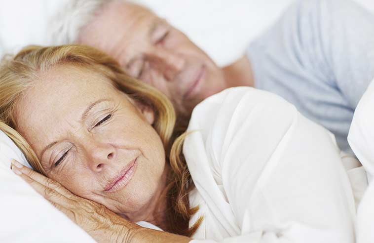 Zufriedenes Seniorenpaar das in einem Bett schläft